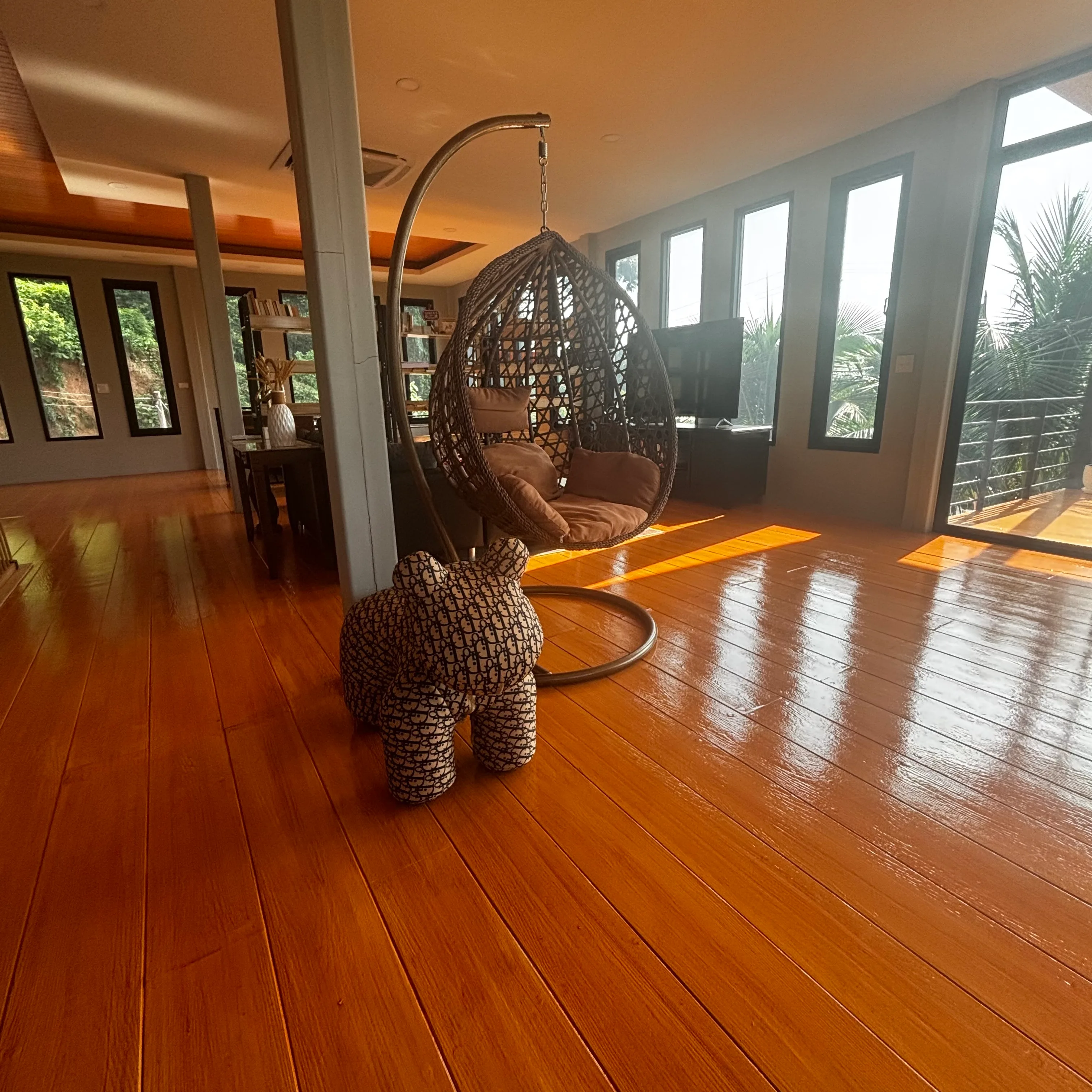 Rattan hanging egg chair on polished hardwood floors in a sunlit open-plan living room