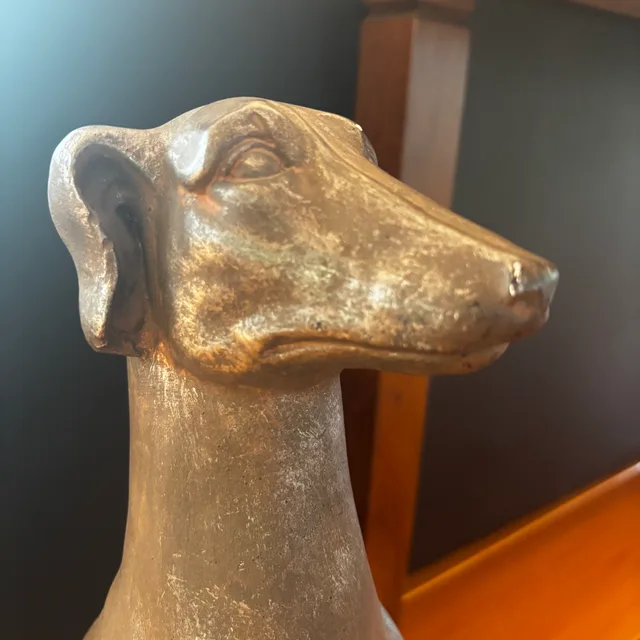 Decorative bronze greyhound statue against dark wooden panelling