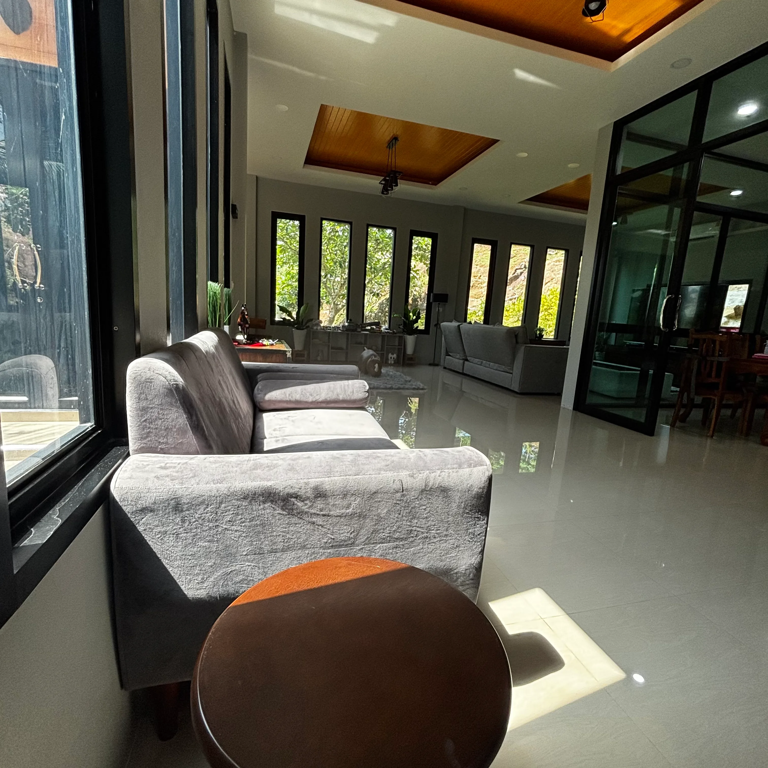 Row of grey armchairs beside floor-to-ceiling windows in an open-plan living space