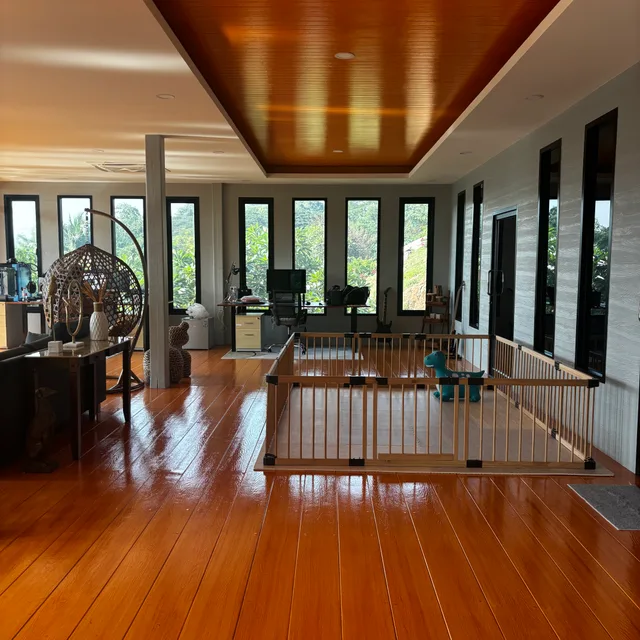 Wide open-plan interior with wooden recessed ceiling, hardwood floors and rows of windows