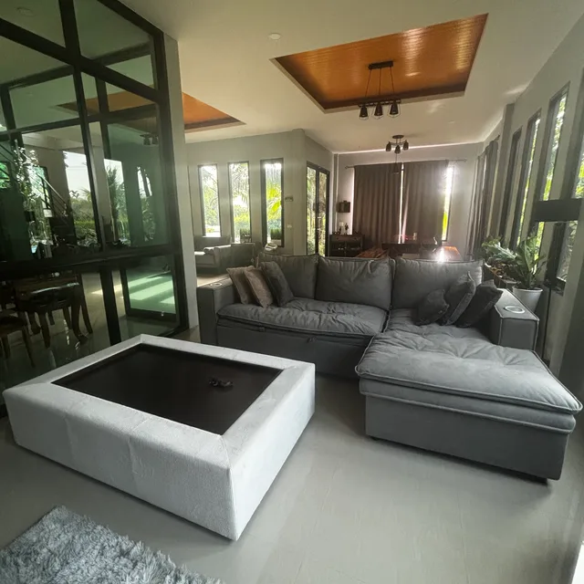 Deep grey sectional sofa with ottoman coffee table in glass-walled lounge